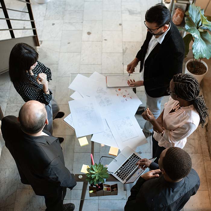 Aerial photo of business people standing around discussing documents