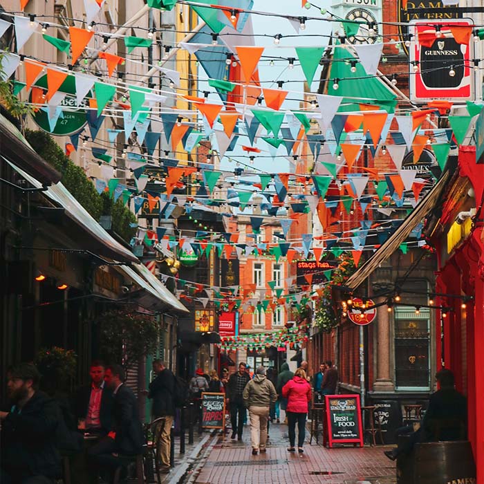 side alley pub and restaurant district in ireland with orange white and green flags