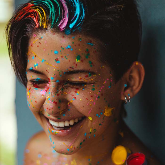 a young woman with rainbow coloured paint in her hair