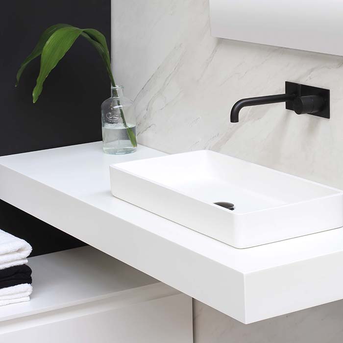 a white basin with a black tap set against white marble
